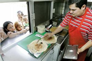 Jorge Campos (right) prepares food for customers at Taqueria Samantha.