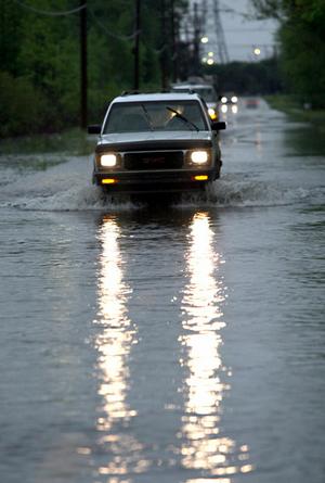 A motorist slowly makes his way through high water covering Faulkner Lake Rd. in North Little Rock Wednesday.