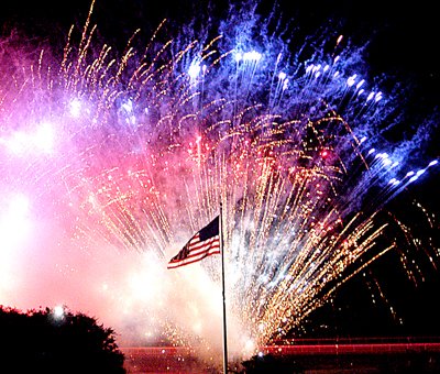 red-white-and-blue-fireworks-explode-as-a-backdrop-to-a-us-flag-during-a-patriotic-display-at-spa-blast-in-hot-springs-at-oaklawn-park