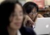 Laid-off public school teacher Natalie Barmore (right) files for unemployment benefits Wednesday online at a job fair sponsored by the school district in Detroit.