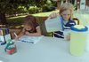 Ivy Wenderski, 6, works on coloring a lemonade sign while her brother, Gage Wenderski, 8, prepares a glass of lemonade for a customer a summer afternoon in front of their Springdale home.