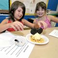 Tabitha Curlin, 9, placed cookies for the ears on her Mouse Creams as Millie Bramel, 9, giggled in t...