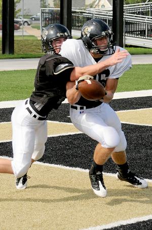 Senior defensive back Christian Larimer, left, tried to strip a pass from senior receiver Sheldon Vanderpool during Bentonville's football practice Friday at Tiger Stadium.