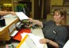 Bridgette Secrist, Washington County deputy circuit clerk, hands papers to a resident after filing paperwork for a case Friday at the Washington County Courthouse in Fayetteville.  The state Legislature increased filing fees for certain lawsuits to fund a new statewide, automated court management system.