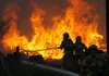 Firefighters work to control a blaze Monday afternoon at Paletta Pallet on Cloverdale Road near Avoca. The fire destroyed three mobile homes, but firefighters were able to prevent flames from spreading to seven others.