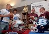 From left, Bryant football players Logan Garland, Jimi Easterling, and Benton players Lee Richardson and Drew McCurry gather around the Salt Bowl trophey during a press conference Tuesday promoting the Sept. 4 football game between the Saline County rivals.