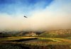 A helicopter draws water to drop on the Lockheed Fire in unincorporated Santa Cruz County, Calif., on Thursday. As of Thursday evening, the fire had burned about 2,800 acres