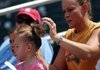 Trish Wood of Cave Springs puts up her 2-year-old daughter Clancey's hair Sunday before watching the Northwest Arkansas Naturals take on the Frisco RoughRiders at Arvest Ball Park in Springdale. The RoughRiders won the game 7-4.