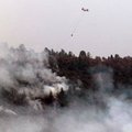 A helicopter drops water on a fire near Dobbins, Calif., on Sunday. According to California fire off...