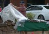 Harry Bryant of Lincoln takes the plastic tarp from his booth at the Fayetteville Farmers Market on Tuesday morning after a brief shower came through the area.