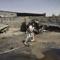 An Afghan man hurries past the scene of a deadly suicide car-bombing Tuesday on the outskirts of Kab...