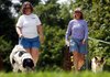 Diane Aldridge of Rogers (left) and her 3-year-old collie mix, Abby, and Julie Carr of Bentonville and her
4-year-old papillon walk Thursday on the trail that runs past U.S. 71B and the Bentonville Bark Park.