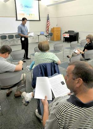 Bill Crawford looked over a list of frequently asked questions about flu viruses before the beginning of the Benton County Community Coalition's monthly meeting at the Rogers Public Library on Thursday.  