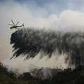 A helicopter drops water Friday as firefighters battle flames in Southern California's Angeles Natio...