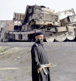 A Pakistani police officer stands next to burned trucks loaded with supplies for NATO forces fighting in Afghanistan after an explosion Monday in Chaman, Pakistan, near the Afghan border.
