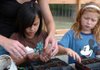 Happy Hollow Green Team members Kaitlyn Agnitti, left, and Zipporah Brechwald get help planting flowers in their new greenhouse Tuesday at the school on Ray Avenue in Fayetteville. The greenhouse was built this summer by employees of the Lowe's store on Martin Luther King Jr. Boulevard.

