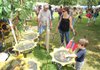 Dean Henry of Highlandville, Mo., describes the bird feeders that he and his wife make from used tires as Wendy McCain of West Fork and her 3-year-old son, Jake, listen during the Clothesline Fair on Sunday in Prairie Grove. 