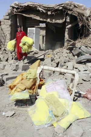  An Iraqi woman carries her belongings out of the ruins of her home after a suicide truck bombing Thursday in the Shiite Kurdish village of Wardek, about 35 miles southeast of Mosul.