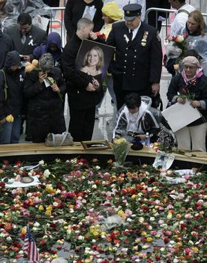 A man carries a photograph of a woman as he joins other mourners around a reflecting pool during a memorial ceremony at the World Trade Center construction site, Friday, Sept. 11, 2009 in New York.