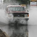 A driver splashes through a puddle during a downpour Monday morning on Walnut St. in Rogers. Rain co...