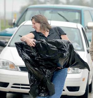 Carolyn Benham of Rogers hurried inside the Crafts Building with her artwork covered in plastic for checkin at the Benton County Fair on Monday. 
 