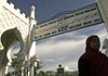 A Muslim woman walks Sunday past a sign advising people to wear Muslim attire at Baiturrahman Grand Mosque in Banda Aceh, Indonesia.