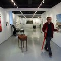 University of Arkansas graduate student and Gallery Director Garry Holstein fixes labels on pieces i...
