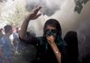 An Iranian opposition supporter (above) walks through a cloud of tear gas Friday during a demonstration in Tehran. 
