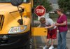 Tyler Davis, left, checks the battery on a school bus as driver Trisha Labit looks on during a safety check of the bus Friday at the Fayetteville School District Transportation Depart- ment in Fayetteville. Davis started his driver training this week, and Labit has been teaching him the rules and regu- lations of driving the bus.