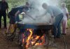 Magda Musur, left, and Billy Bower skim non-edible material off the top of cooking liquid sorghum as they help make sorghum molasses Saturday at the Cane Hill Harvest Festival. The festival continues today in Canehill.
