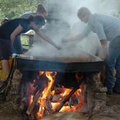 Magda Musur, left, and Billy Bower skim non-edible material off the top of cooking liquid sorghum as...