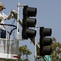 City of Fayetteville employee Greg Biswell installs a camera above one of the traffic signals Monday...