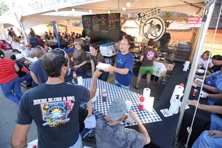 
                               
                                  Photo by Andy Shupe&mdash;
                               
                           
                           Don Bennett, a friend of the owner of Lucky Luke's BBQ, center, hands a sample rib to H.P. Wright, of Stilwell, Okla., as workers serve visitors to the 10th annual Bikes, Blues & BBQ motorcycle rally Friday in Fayetteville.