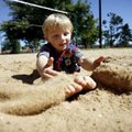 Jon Holmesmith, 5, of Pea Ridge buries his legs while playing in the volleyball pit Tuesday at Murph...