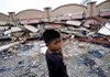 A boy in Padang in Indonesia's West Sumatra province stands Thursday near a flattened building. The country has been hit by two earthquakes this week, the second on Thursday. 