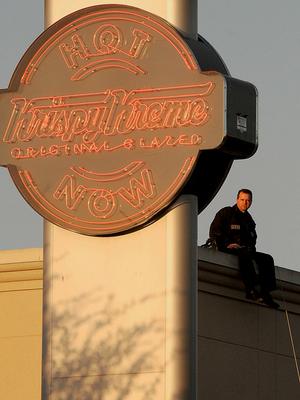 Bentonville Police Detective Mark Jordan sat atop the Krispy Kreme donut shop in Bentonville on Saturday while Lincoln Junior High School volunteers below sold T-shirts and took donations for the Arkansas Special Olympics.