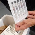 A nurse holds vials from the first shipment of vaccine for swine flu, which arrived at the Arkansas ...
