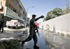 An Afghan policeman keeps journalists away from the scene of a suicide car-bombing Thursday outside the Indian Embassy in Kabul.
