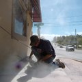 Kevin Jones, with Colored Surfaces Co., sands the paint off the steps in front of the Psychic Reader...