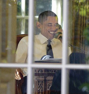 President Barack Obama takes a call in the Oval Office on Friday before speaking to the nation about his Nobel Peace Prize.