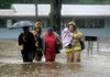 Little Rock firefighter William Bowden (right) carries a child Friday as he and another firefighter help two employees of the Dreamland Child Development Center at 7722 Stagecoach Road make their way to safety after water surrounded the business.