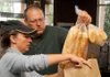 Volunteer Kay Scott from Kay’s Kitchen and Rick Boosey loaded a bag with food for a family of five at Boosey’s Bentonville restaurant, World Garden, on Sunday. Others were preparing food in the restaurant kitchen for delivery to the Northwest Arkansas Women’s Shelter and other area charitable organizations. 

