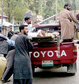 Pakistani police officers push a vehicle carrying an injured person after a suicide bombing in Shangla, Pakistan, on Monday.
