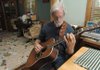 Jack Williams, a nationally known folk musician and singer-songwriter, plays his guitar in his home near West Fork. Williams will participate in a musician’s workshop Oct. 23-25 with Still on the Hill. He will also make a rare local appearance Nov. 20 at Goodfolk Production House in Fayetteville with Ronny Cox, the actor known for playing “Dueling Banjos” in the 1972 movie “Deliverance.” 