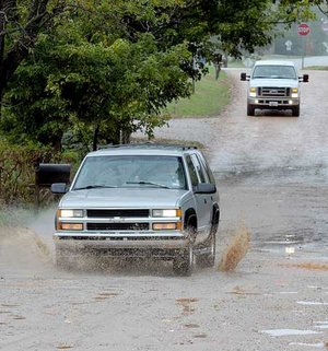 The driver of a sport utility vehicle bounced and splashed its way through the ruts and puddles on Elk Road in Cave Springs on Tuesday. 

