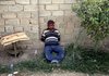 A suspected Iraqi insurgent who authorities say rigged a number of vehicle bombs is detained outside a house near Baghdad on Wednesday after a raid by Iraqi forces who said they also found a partially assembled bus bomb.
