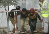 A Pakistani policeman helps a man outside a police training center on the outskirts of Lahore, where four militants killed 11 officers Thursday before being killed by police.
