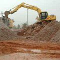 Workers with Rolling Rock Recycling LLC use their remote-controlled mobile rock crusher to turn the ...