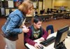 Sixth-grade math teacher Karen Bradshaw helped Kyle Davison, 11,  of Rogers sign in to a program during the first official day of the Excel period at Kirksey Middle School in Rogers on Wednesday. Based on last spring’s Benchmark scores, students who were proficient or lower were put in targeted classes to get extra help, while advance students were able to pick a class of their choice. 