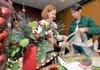 Nancy Evans, left, and Sara Herlevic with the Junior Auxiliary of Rogers-Bentonville wrapped posters around boxes of candy canes at Panera Bread in Bentonville on Monday morning. 